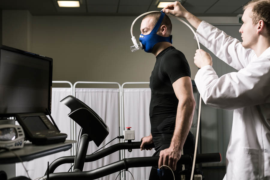 doctor connecting medical monitoring equipment to a man on a treadmill
